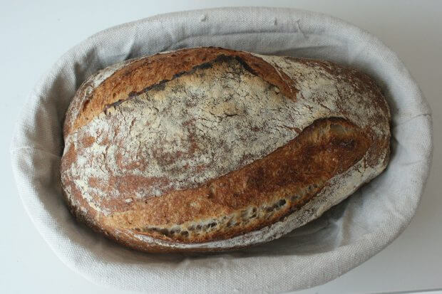 o pâine făcută din maia pusă într-un coș, pe o pânză albă.
